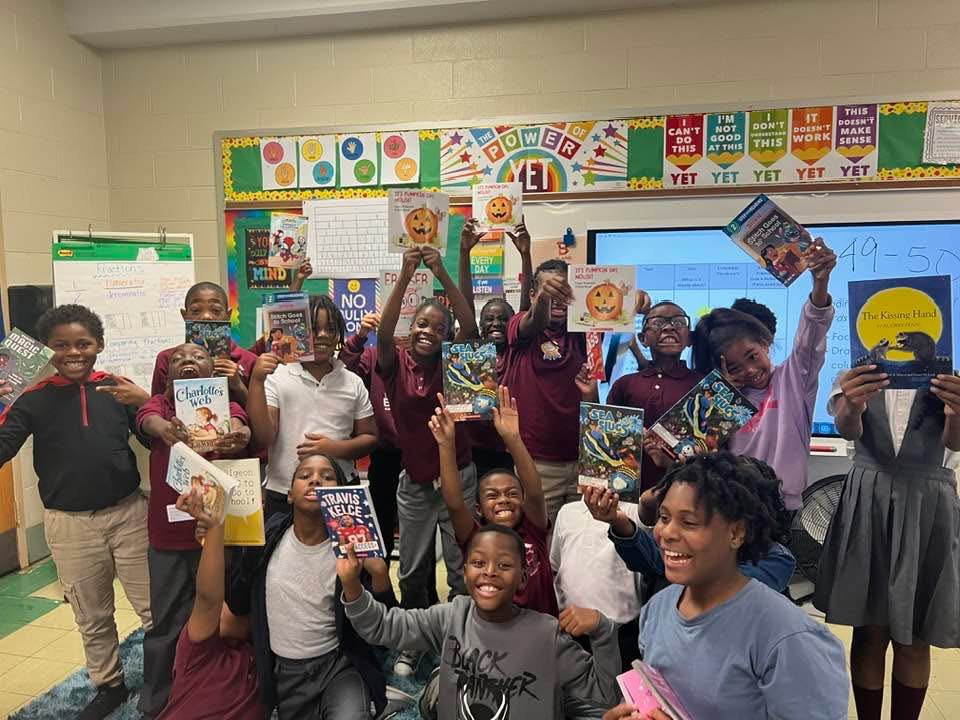Students holding up books at a Mansion Coalition community program
